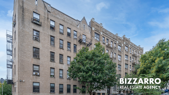 Front view of a multi-story brick apartment building with fire escapes.