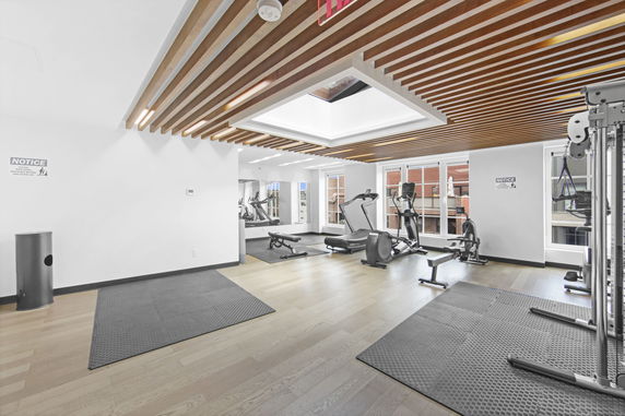 Interior view of a gym with exercise equipment and wooden ceiling design.