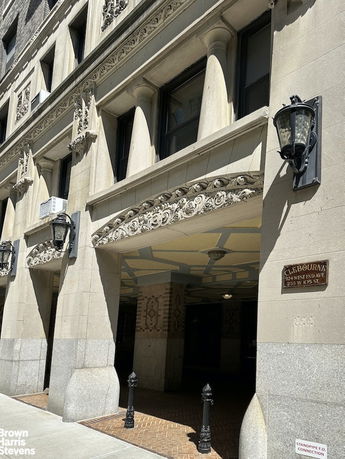 Front view of a stone-clad multi-story building entrance with ornate architectural details.