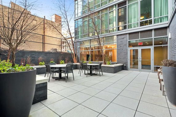 Outdoor seating area adjacent to a modern glass building with large planters.