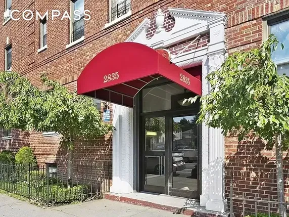 Front view of a brick building entrance with a red canopy.
