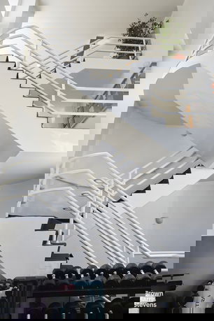 Interior view of a modern staircase in a fitness area with gym equipment.