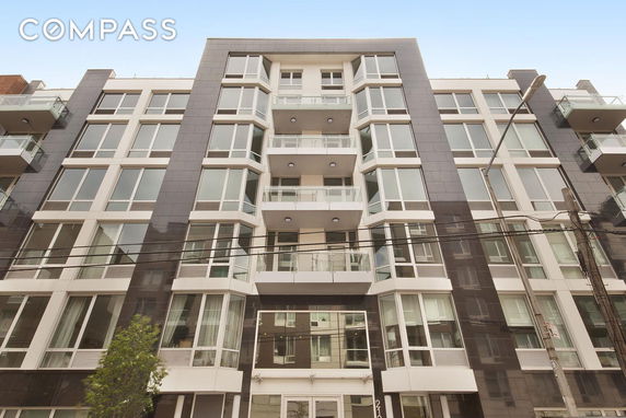 Front view of a modern multi-story apartment building with large windows and balconies.