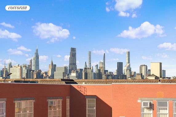 City skyline with multiple skyscrapers under a blue sky view from a rooftop.
