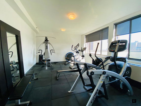 Room with gym equipment including exercise bikes and a weight machine.