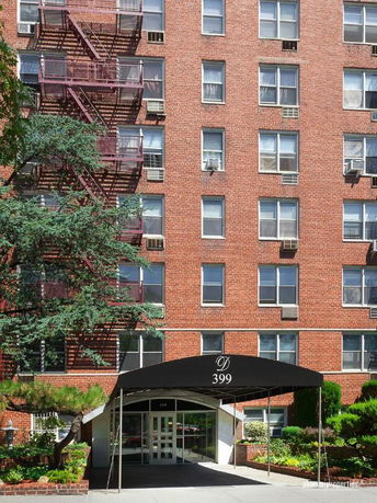 Front view of a brick apartment building with multiple windows and a black canopy marked '399'.