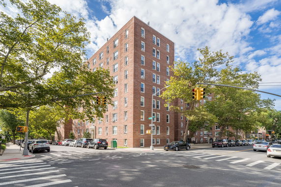 Front view of a multi-story brick apartment building on a city corner.