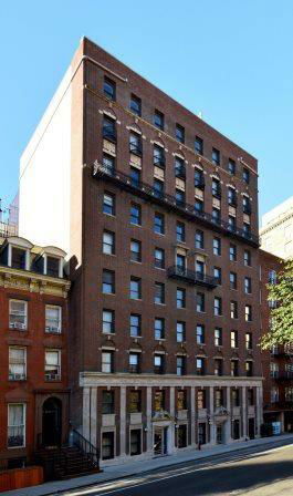 Front view of a multi-story brick building with multiple windows and balconies.
