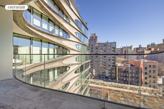 A view from a balcony showing a modern building with curved architectural features and large windows, set against a cityscape background.