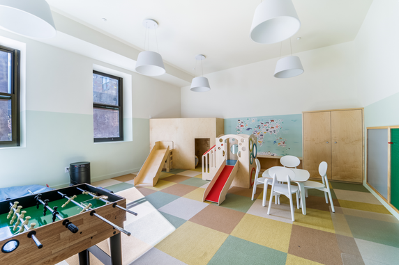 Indoor children's play area with slides, a table and chairs, and a foosball table.