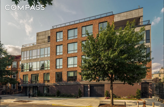Front view of a multi-story brick and concrete building with large windows.