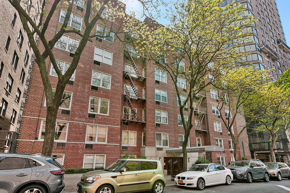 Front view of a multi-story brick apartment building with fire escapes.