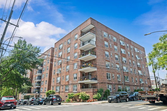Front view of a multi-story brick apartment building with balconies.
