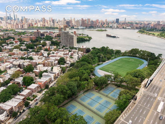Panoramic view of a city with sports fields and a river.