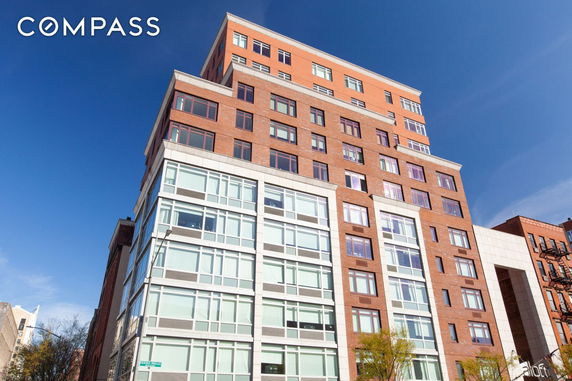 Front view of a multi-story building with a modern design featuring large windows and a brick facade.