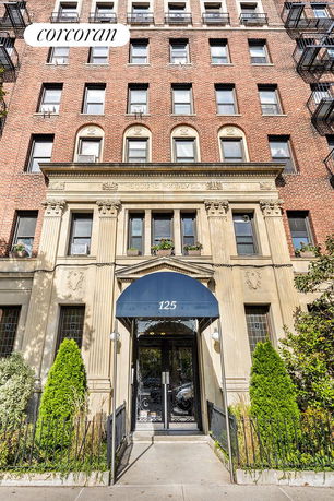 Front view of a multi-story brick building with decorative facade and entrance canopy.