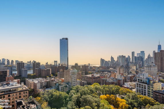 Panoramic cityscape view featuring skyscrapers and a bridge.