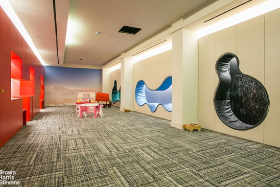 Indoor play area with colorful wall designs and children's furniture.
