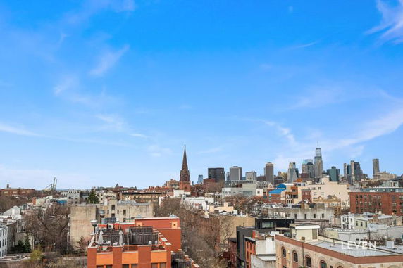 Panoramic view of cityscape with a mix of low-rise and high-rise buildings against a blue sky.