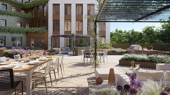 Rooftop area with dining tables, lounge seating, and a barbecue grill, adjacent to a modern building facade.