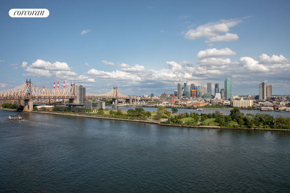 Panoramic view of a city skyline with a river and bridge in the foreground.