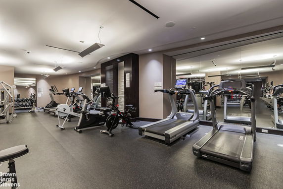 Indoor gym with treadmills, exercise bikes, and weight equipment.
