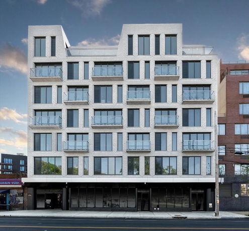 Front view of a modern multi-story apartment building with balconies.