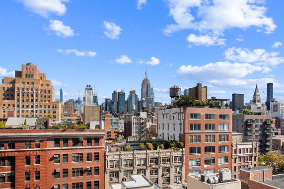 Panoramic view of city buildings and skyscrapers under a blue sky.