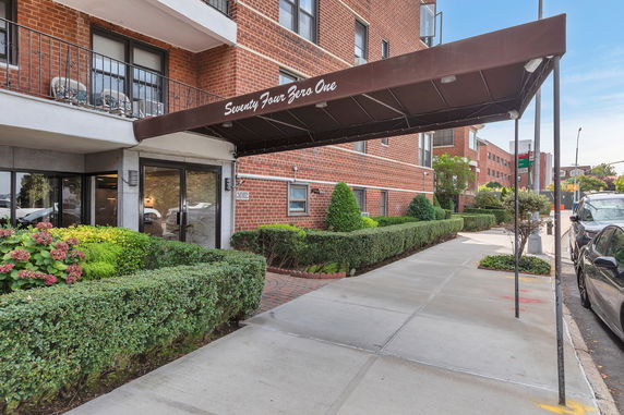 Front view of a brick apartment building with an entrance canopy and landscaped area.