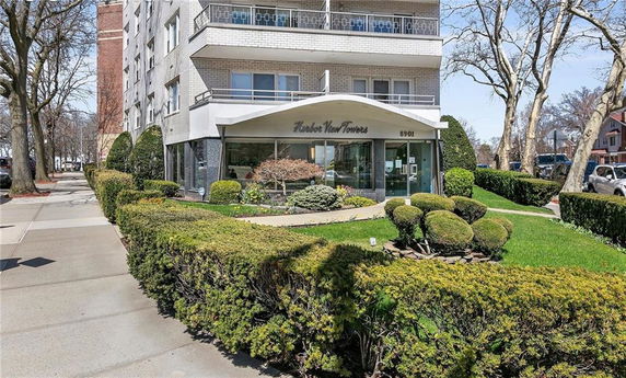 Front view of a multi-story residential building with balconies and landscaped entrance.