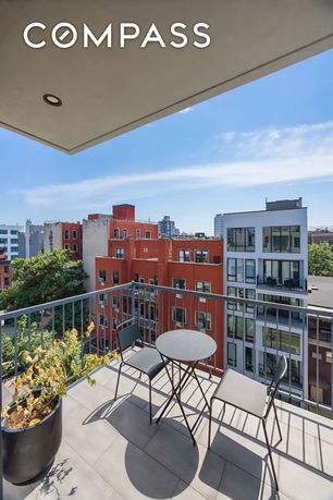 View from a balcony with outdoor furniture overlooking city buildings.