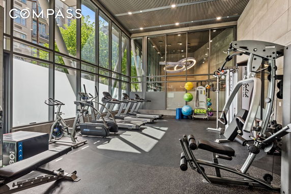 Indoor gym area with exercise equipment and large windows.