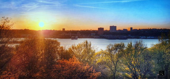 Sunset view over a river with city skyline in the background.