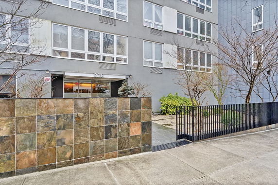 Front view of a multi-story building with large windows and a tiled wall.