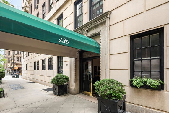 Front view of a building entrance with green awning and decorative plants.