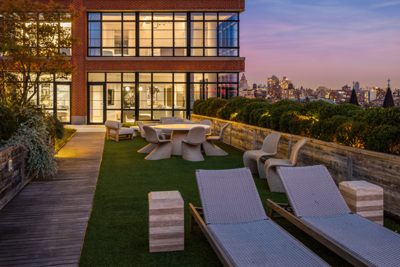 Rooftop with outdoor seating area and greenery on a building.