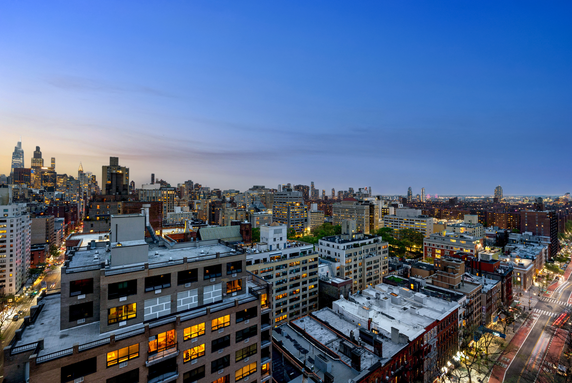 Panoramic view of cityscape at dusk with illuminated buildings and streets.