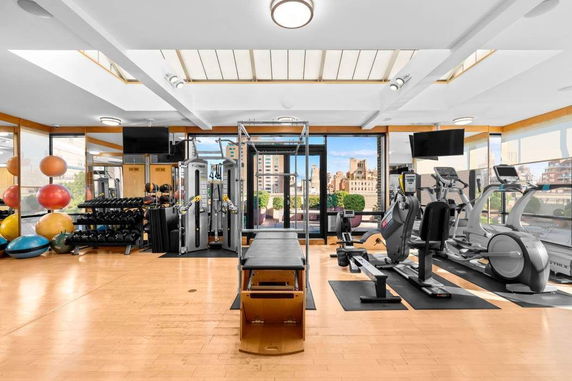 Gym area with various fitness equipment and large windows.