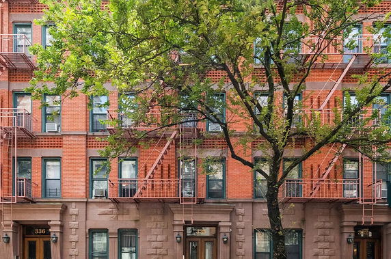 Front view of a brick apartment building with fire escapes.