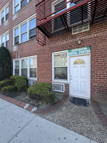 Front view of a commercial building with brick walls and multiple windows, featuring a sign for Kensington Dental Center.