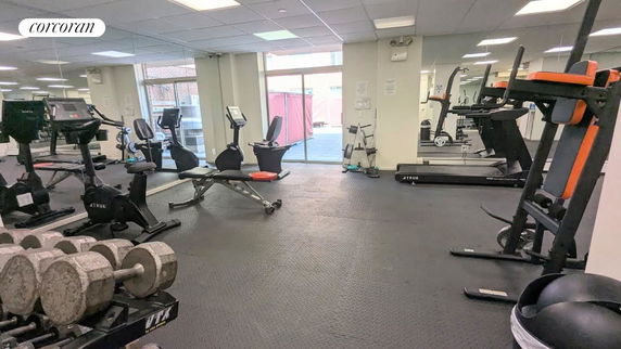Indoor gym area with exercise equipment including treadmills, bikes, and weights.