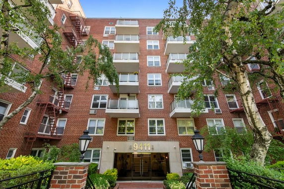 Front view of a multi-story brick apartment building with balconies.