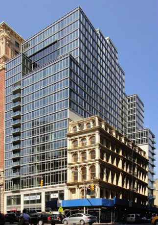 Front view of a modern glass high-rise building next to an older style building.