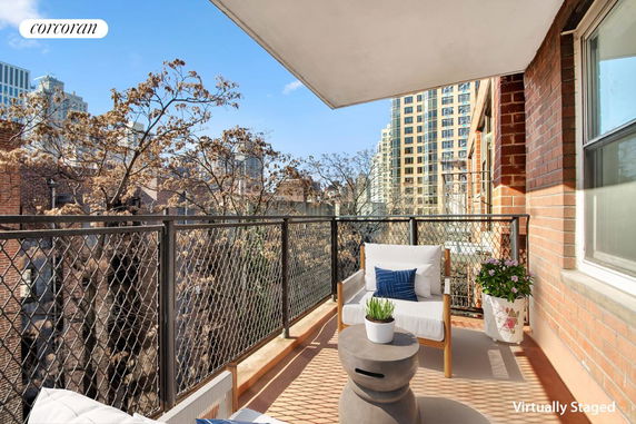 Balcony view of a residential building with surrounding tree tops and other buildings in the background.