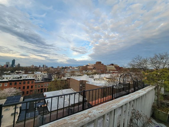Wide angle view of urban rooftops and distant buildings under a cloudy sky.