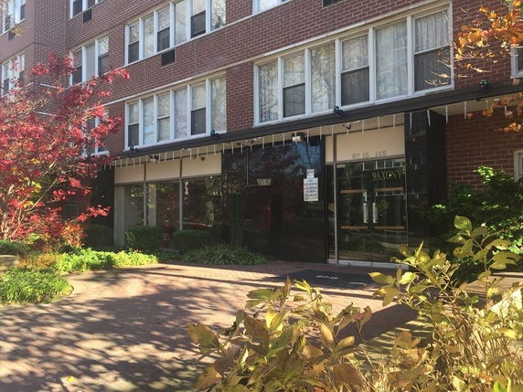 Front view of a multi-story brick building with large windows.