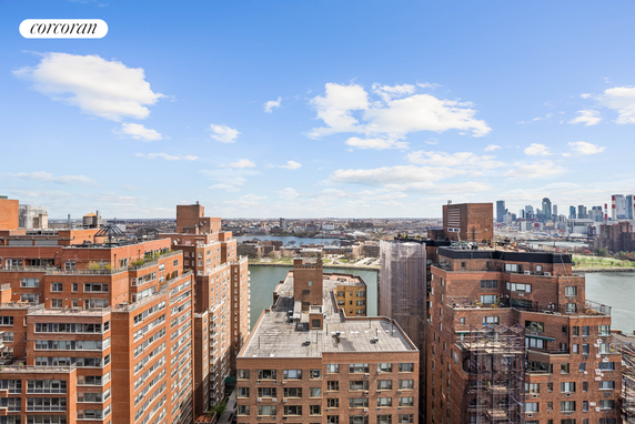 Panoramic view of city buildings with a river and skyline in the background.
