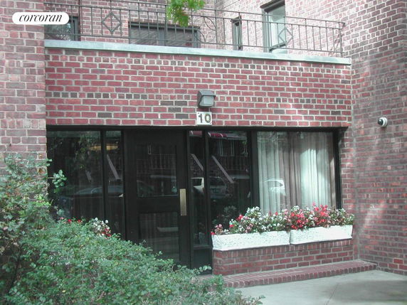 Front view of a brick building with flowers on the windowsill.