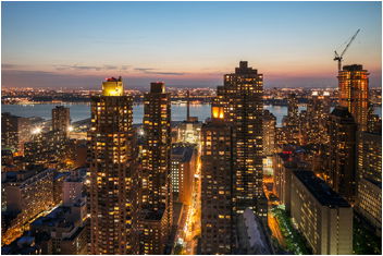 Panoramic view of a cityscape with tall buildings at sunset.