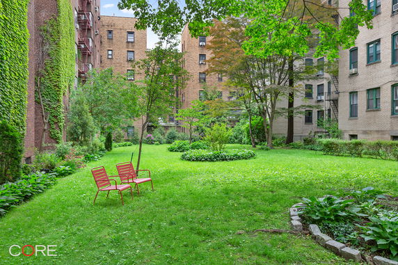 View of a grassy courtyard surrounded by multi-story brick buildings with fire escapes.